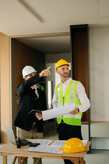 Contractor and architect looking at plan tablet laptop and talking about work